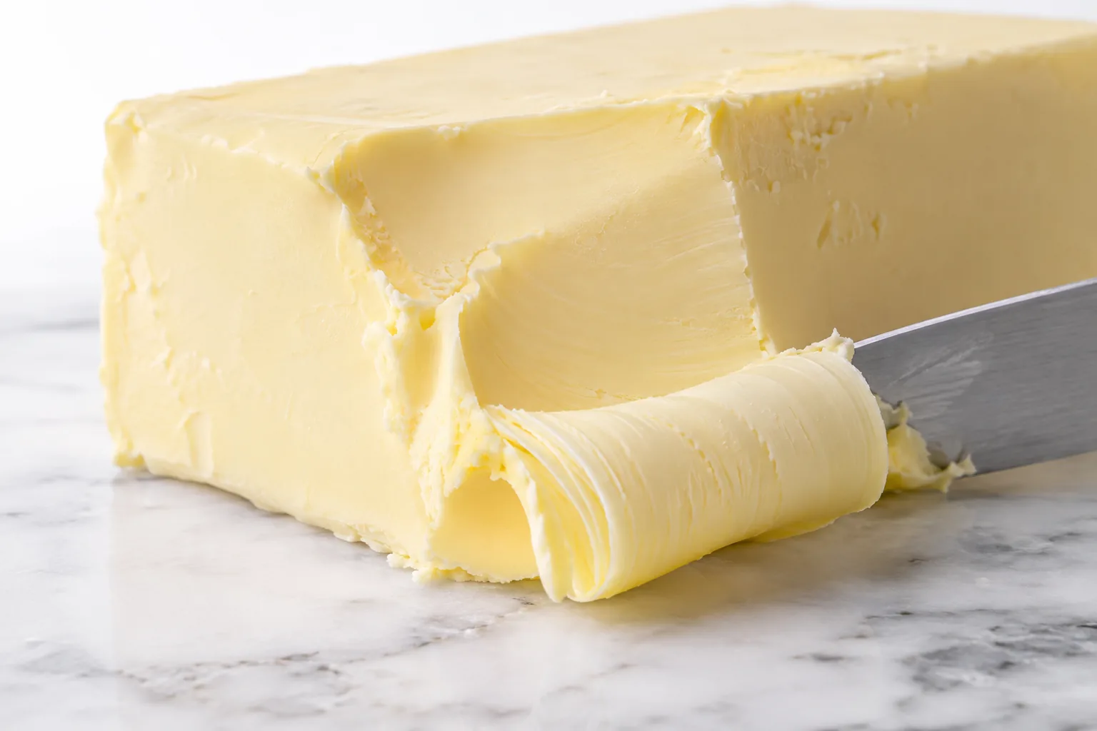 A block of shortening with a smooth curl cut by a knife